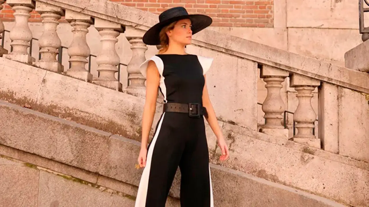 Alejandra de Rojas, con sombrero negro y elegante mono, posa en unas escaleras de piedra.