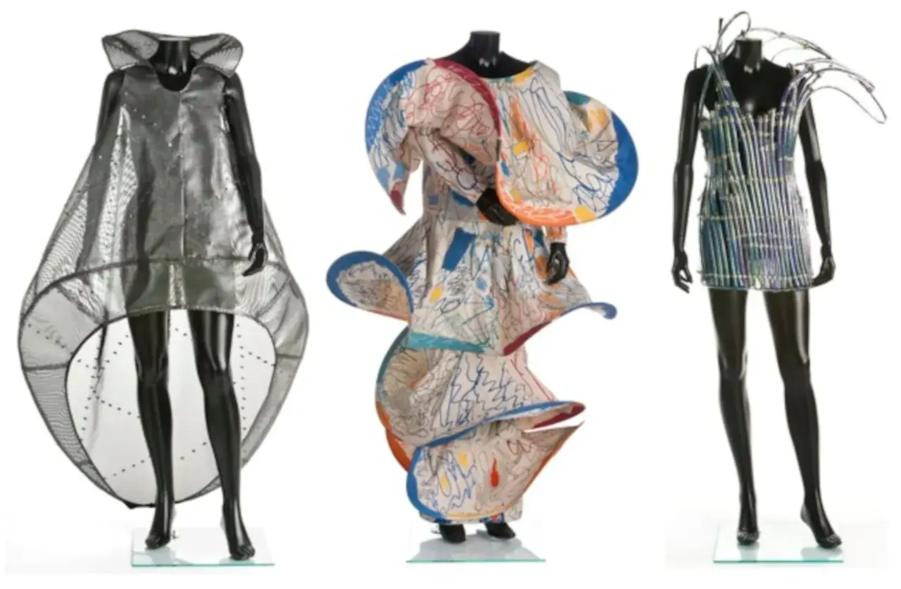 Tres vestidos de diseño: uno plateado futurista, otro con estampado de garabatos de Manuel Piña, y uno azul metálico con detalles de alambre.
