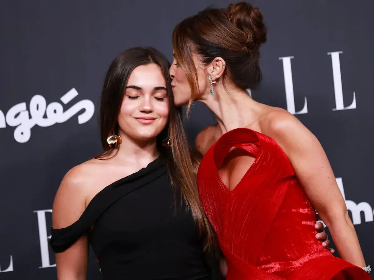 Daniella Bustamante recibe un tierno beso en la frente de su madre, ambas luciendo elegantes en un evento.