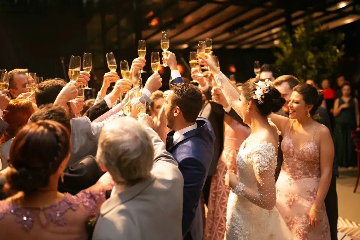 Una multitud celebra un brindis con copas de champán, todos vestidos para un evento de dress code cocktail.