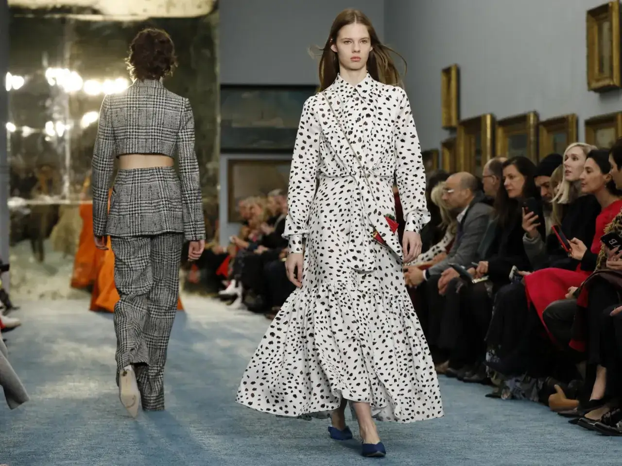 Desfile de moda. Una modelo luce un vestido blanco con estampado de manchas oscuras, evocando la elegancia de quien es Carolina Herrera.