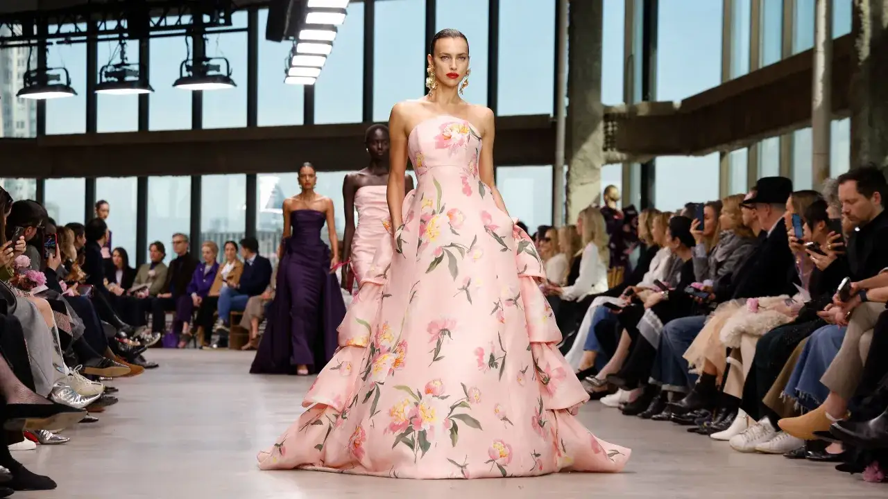 Desfile de Carolina Adriana Herrera: modelo luce un vestido rosa con flores, mientras el p&uacute;blico observa.