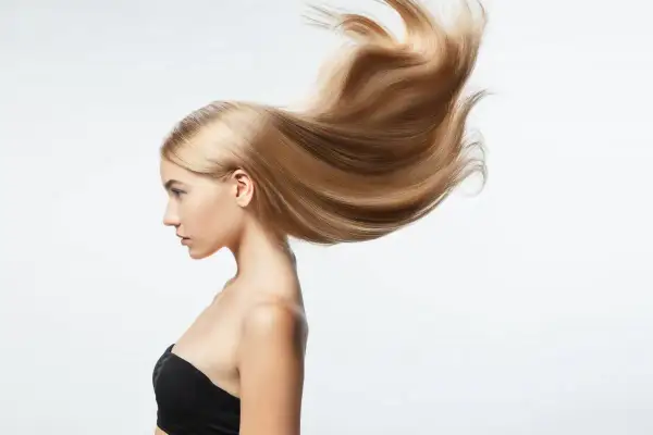 Perfil de mujer con pelo largo rubio y sedoso que se mueve con el viento.
