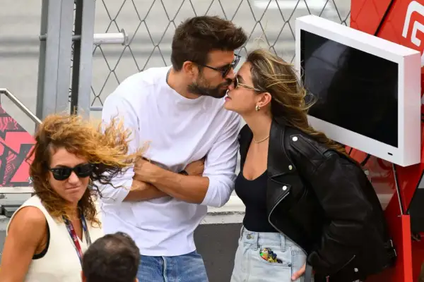 Piqué y Clara Chía se besan apasionadamente, ajenos a la mujer con pelo rizado y gafas de sol que les mira de reojo.