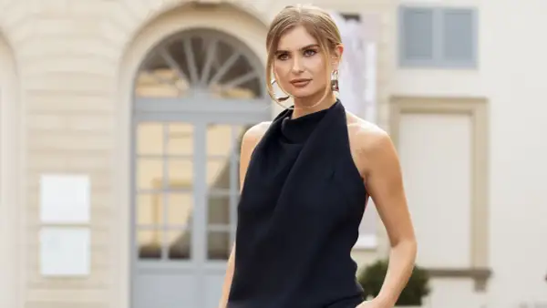 Mujer con un elegante vestido de negro, luciendo unos llamativos pendientes dorados.