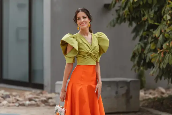 Elegante look invitada boda otoño: top verde con volantes y falda naranja.