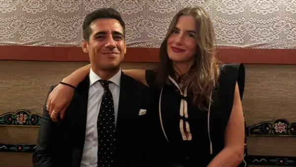 Pareja sonriente, él con traje y corbata de puntos, ella con vestido negro. Blanca Llandres, un momento íntimo capturado.