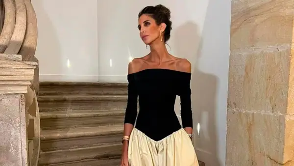 Inés Domecq posa con un elegante vestido negro de escote Bardot y falda voluminosa color crema, luciendo joyas doradas.