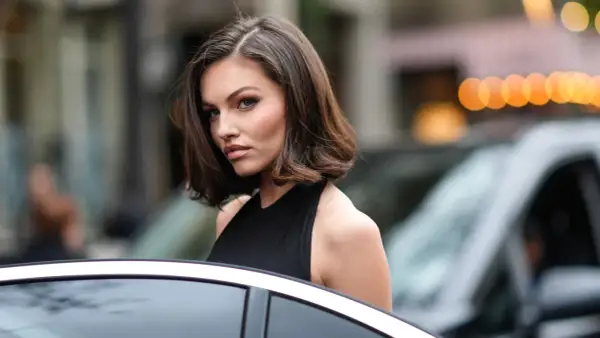 Mujer con corte bob asimétrico, ideal para cortes de pelo para cara redonda, luciendo elegante junto a un coche.