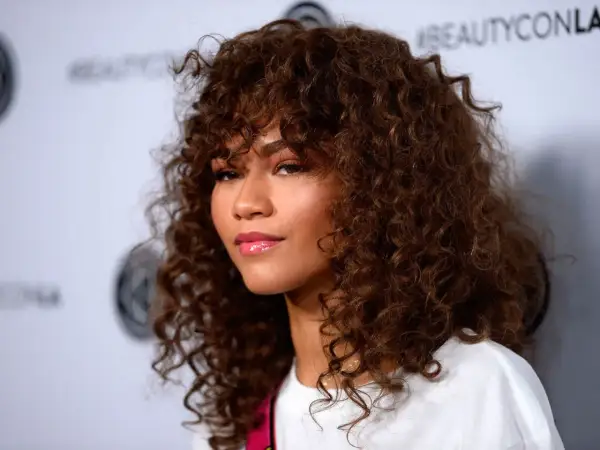 Mujer con pelo muy corto rizado natural, castaño y voluminoso, con flequillo.