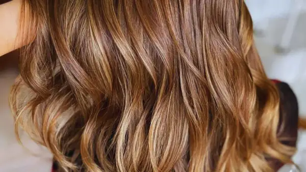 Cabello castaño con mechas babylight sutiles que aportan luz y dimensión, creando un efecto natural y radiante.