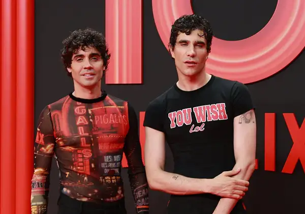 Javier Calvo y Javier Ambrossi posan sonrientes. Javier Calvo lleva una camiseta con estampado de luces de neón y Javier Ambrossi una camiseta negra con el lema "You Wish Lol".