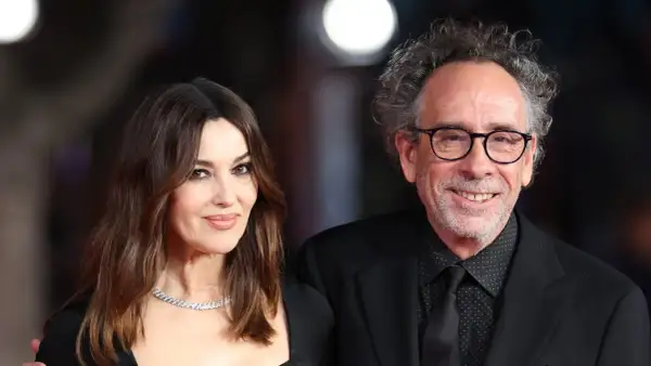 Monica Bellucci y Tim Burton, una pareja que parece sacada de una película de fantasía gótica, posan juntos con elegancia.