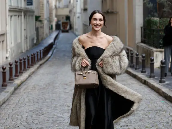 Elegante mujer con abrigo de pelo y bolso, lista para una boda en invierno.