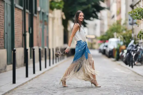 Mujer con falda larga de flecos y top blanco, lista para la feria de abril sin vestido.
