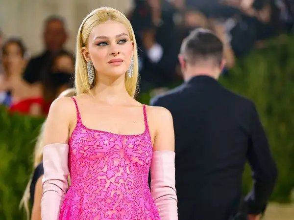 Nicola Peltz deslumbra con un vestido rosa vibrante y guantes a juego, luciendo elegante y radiante.